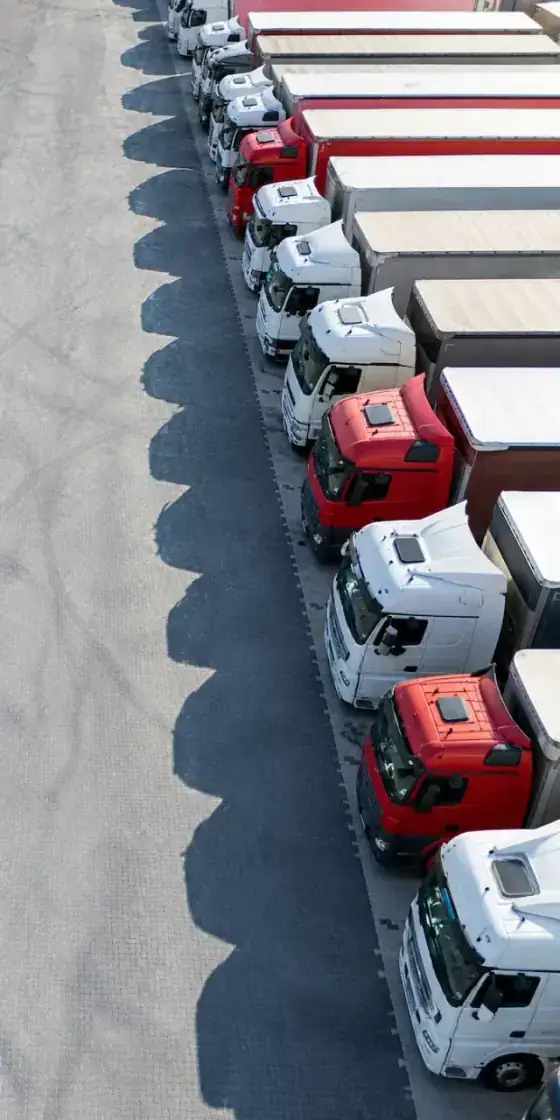 Overhead view of a row of white and red semi-trucks parked in a freight yard.