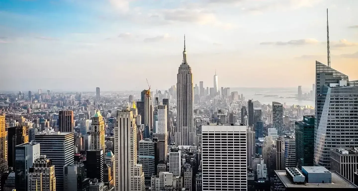 The Manhattan skyline from above at sunrise, with the Empire State Building in the centre and One World Trade Center on the horizon.